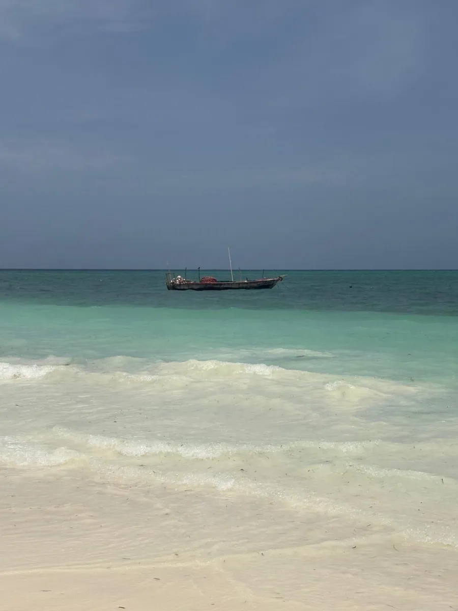 Plage de sable blanc avec dhow au large